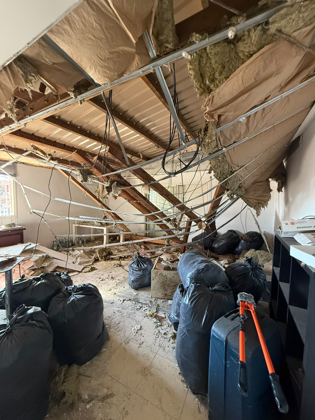 Ancien faux plafond déposé, isolant pendant et sacs de gravats au sol